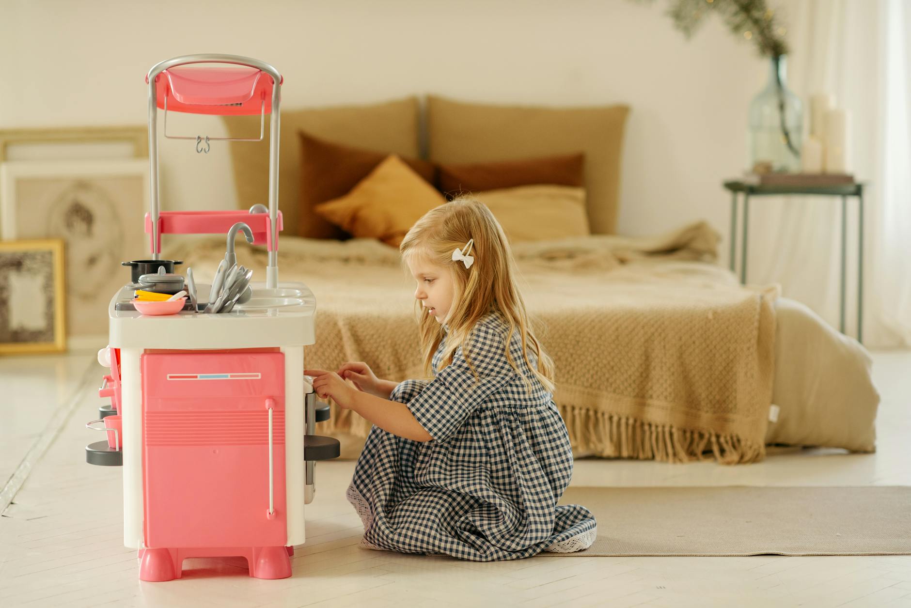 Dziewczynka w kraciastej sukience bawi się w kuchnię w przytulnym pokoju