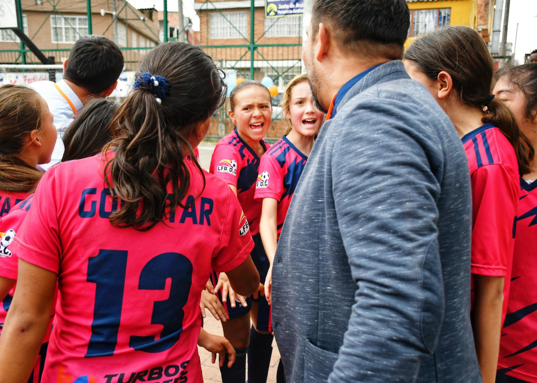 Trener motywuje młodą drużynę piłkarską w grupowym kręgu na boisku