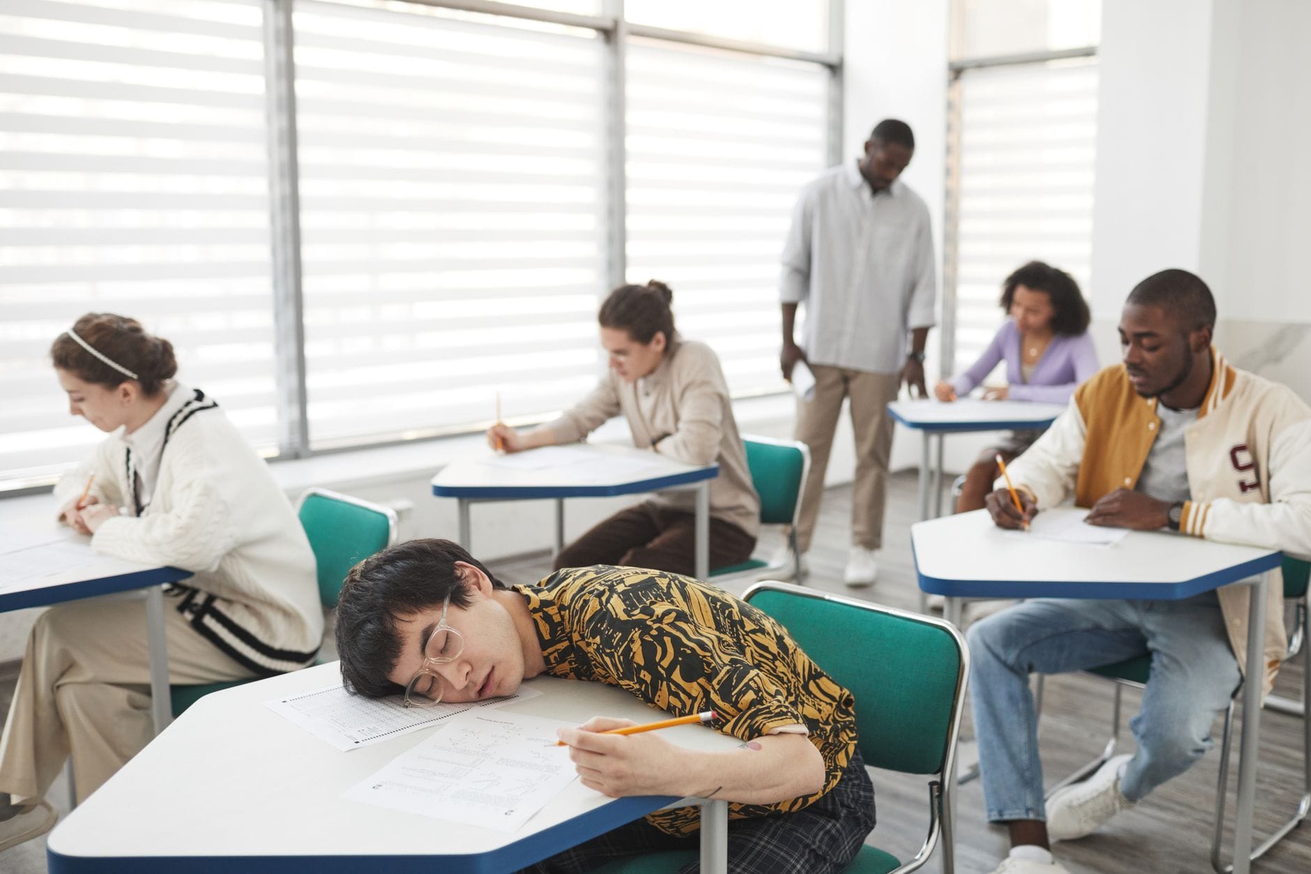 Studenci w sali egzaminacyjnej w skupieniu piszą test